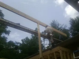 Carpenter setting a ridge beam over a new addition frame — Ice Dam Removal by Roofing Brothers in Wynantskill