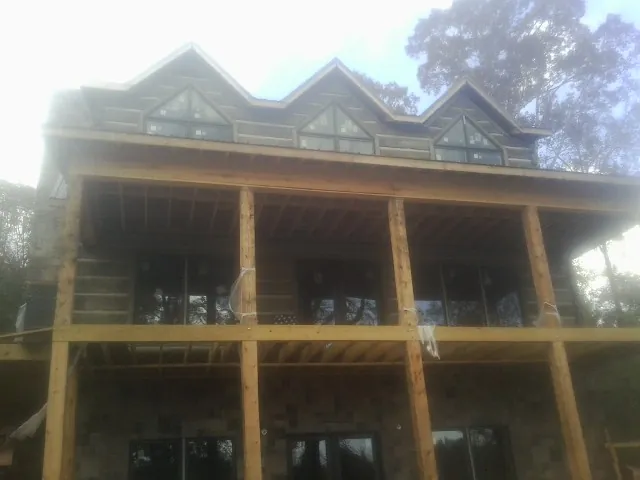Dormers and porch framing on a large log home under construction — Roof Coating work by our crew in Wynantskill
