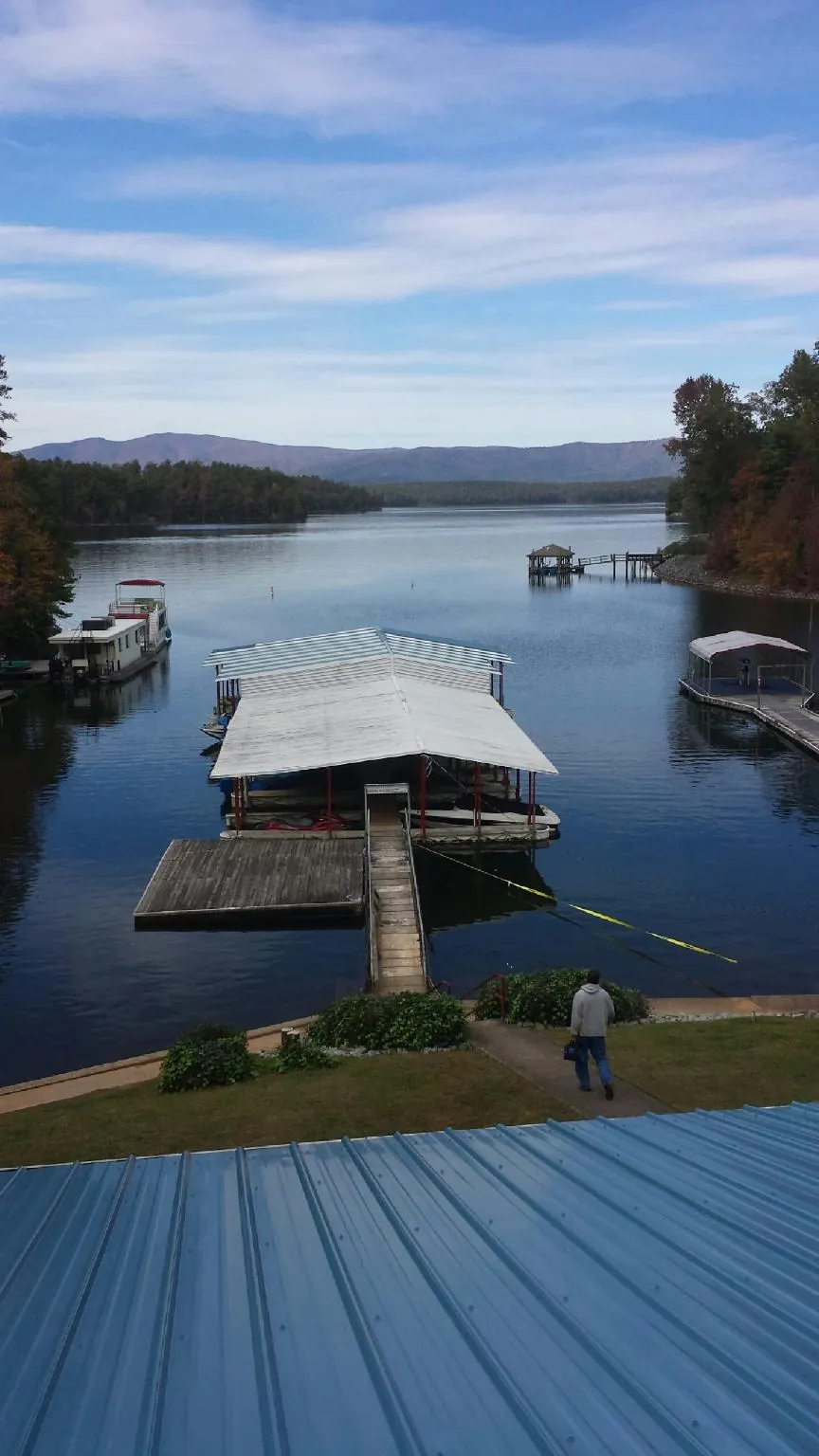 View across a lake from a newly installed blue metal roof in Wynantskill