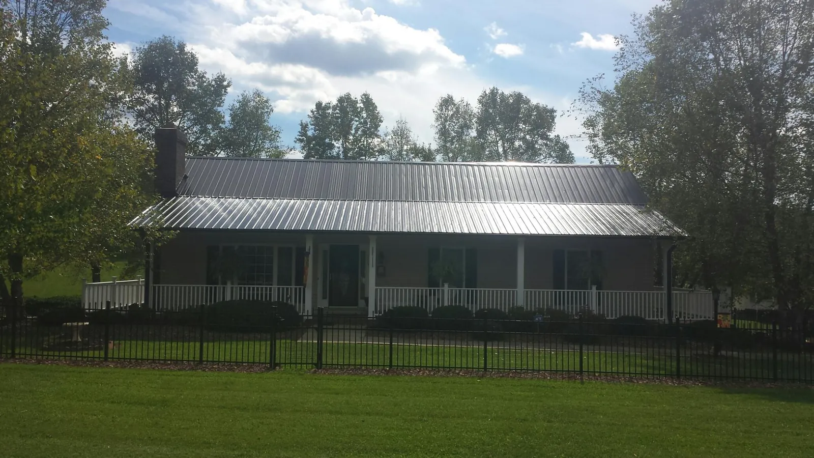 Gray metal roof on a brick ranch with a full width front porch — Gutter Guard Installation work by our crew in Wynantskill